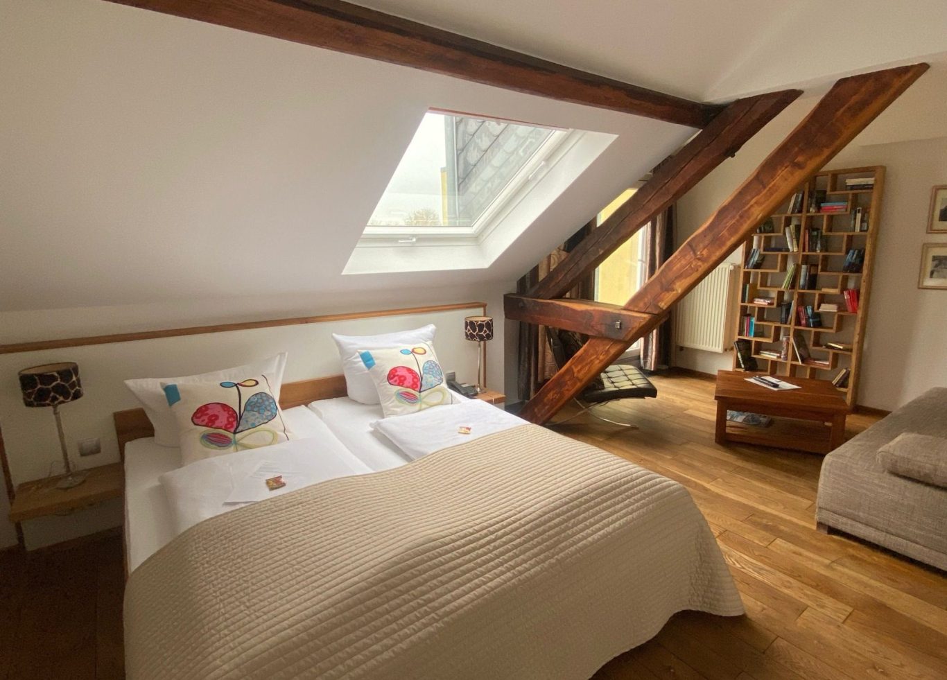 Helles Schlafzimmer mit Dachfenster, Doppelbett und Holzdetails im modernen Stil. Unser Bücherzimmer Nummer 30